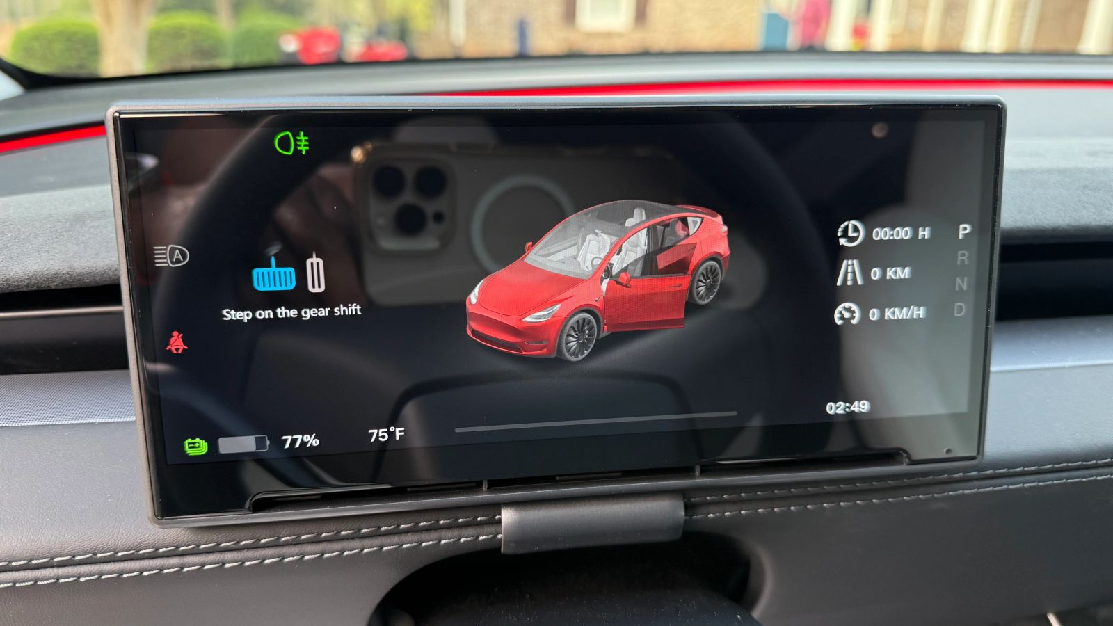 A dash cluster display installed behind the steering wheel of a Tesla, showing speed, gear and range