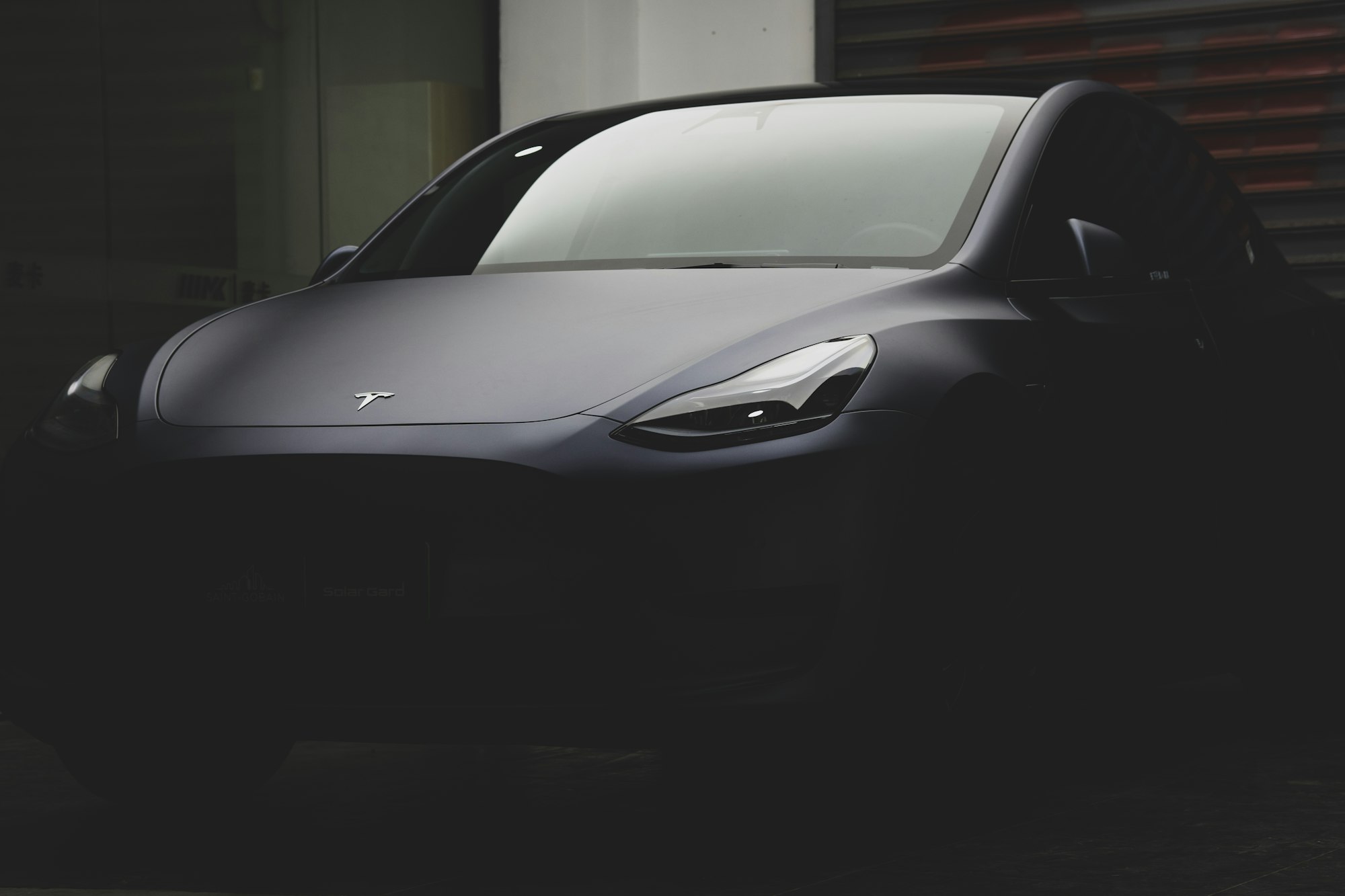 A dark Tesla Model Y lit from one side